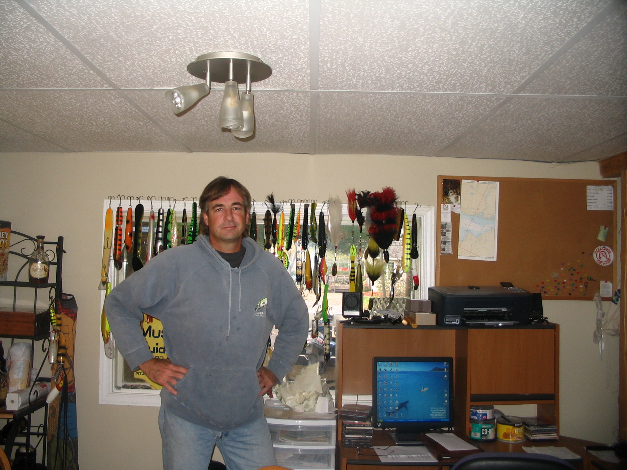 Photo of John Anderson standing in front of his curtains made up of Musky crank baits